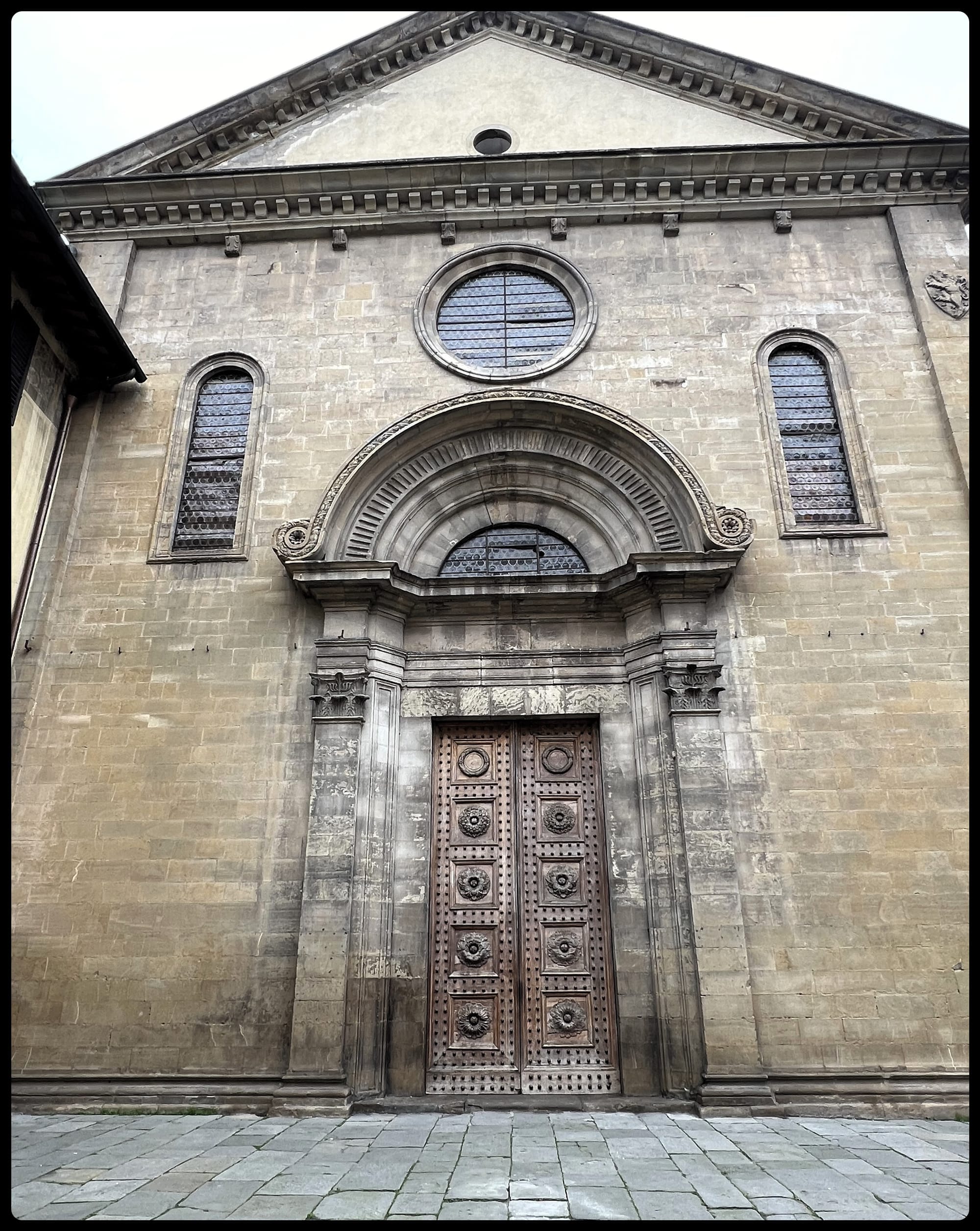 A view of the front doors and front facade of the Chiesa di San Felice, a church in Florence's Oltrarno neighborhood, first built in the eleventh century.